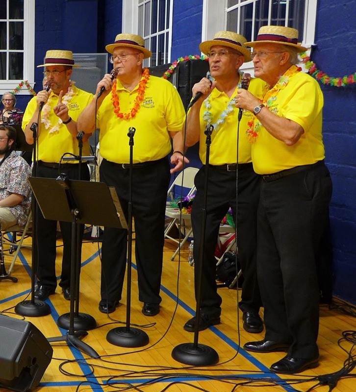 MintConditionYellowMics Mint Condition singing at a tropical-themed event.